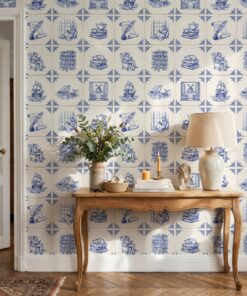 Azulejo wallpaper with bookish tiles behind a carved wooden console table with a linen lamp