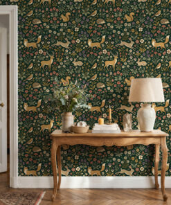 Green millefleur menagerie wallpaper behind a carved wooden console table with a linen lamp