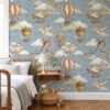 Hot air balloon wallpaper with animal aviators in a kids bedroom with a wooden spindle bed