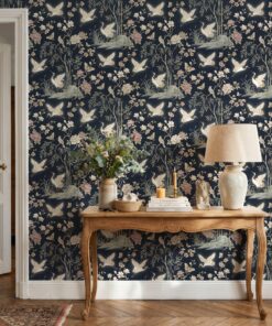 Navy crane chinoiserie wallpaper behind a carved wooden console table with a linen lamp