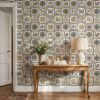 Spanish tile wallpaper with colorful animal azulejos behind a carved wooden console table with a linen lamp