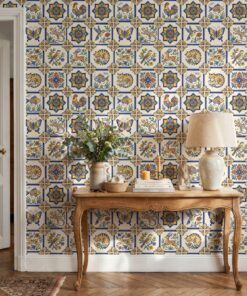 Spanish tile wallpaper with colorful animal azulejos behind a carved wooden console table with a linen lamp