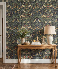 Navy William Morris style bird and strawberry wallpaper behind a carved wooden console table